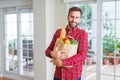 Handsome man holding paper bag full of fresh groceries at home Royalty Free Stock Photo