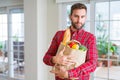 Handsome man holding paper bag full of fresh groceries at home Royalty Free Stock Photo