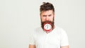 Handsome man holds the clock with his mouth. Crazy bearded hipster with clock. Brutal bearded guy with alarm clock on white