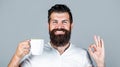 Handsome man holds cup of coffee, tea. Bearded man smiling showing sign ok. Good morning, man tea, ok. Smiling hipster Royalty Free Stock Photo
