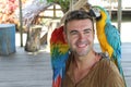 Handsome man interacting with two gorgeous macaws Royalty Free Stock Photo