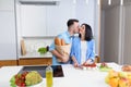 Handsome man kisses his wife holding grocery bags from the store in the kitchen.