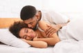 Handsome man kissing woman on cheek under in bed Royalty Free Stock Photo