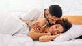 Handsome man kissing woman on cheek under in bed Royalty Free Stock Photo