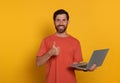 Handsome man with laptop showing thumb up gesture on orange background Royalty Free Stock Photo