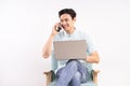 Handsome man with laptop sitting on sofa listening to the phone and working Royalty Free Stock Photo