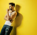 Handsome man leaning on the bright, yellow wall