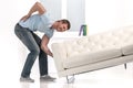 Handsome man lifting sofa and feeling pain.