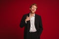 Handsome man with lipstick marks on face posing isolated over red wall