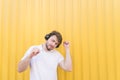 Handsome man listens to music in wireless headphones and dances against the backdrop of a yellow wall. Musical concept Royalty Free Stock Photo