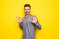 Handsome Man is a little bit nervous and scared stretching hands to the front on isolated vibrant yellow color Royalty Free Stock Photo