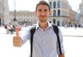 Handsome man looking at camera and thumbs up in city street