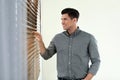 Handsome man looking through window blinds Royalty Free Stock Photo