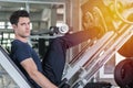 Handsome man lowering weight training legs on leg press machine and working out in the fitness gym Royalty Free Stock Photo