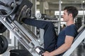 Handsome man lowering weight training legs on leg press machine and working out in the fitness gym Royalty Free Stock Photo