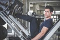 Handsome man lowering weight training legs on leg press machine and working out in the fitness gym Royalty Free Stock Photo