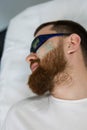 Handsome man is lying on a bed at the cosmetologist& x27;s office, prepares him for a laser hair removal procedure on Royalty Free Stock Photo