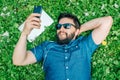 Handsome man lying on green grass in the park and listening music Royalty Free Stock Photo
