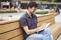 Handsome man making notes in a book sitting outside. Royalty Free Stock Photo