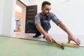 Handsome repairman measuring wooden flooring with hammer install laminate