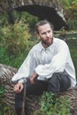 Handsome man in medieval costume sitting on the tree Royalty Free Stock Photo