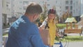 Handsome man open door to a food delivery woman wearing yellow thermal backpack on a bike and recieves order or package Royalty Free Stock Photo