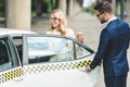 handsome man opening car door while smiling blonde woman with paper cup sitting Royalty Free Stock Photo