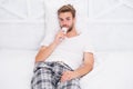 Handsome man in pajama with remote control. guy watching television in bedroom. lazy sunday at home. watch morning show Royalty Free Stock Photo