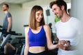 Handsome man personal trainer helping fit woman working with dumbbells in fitness gym club Royalty Free Stock Photo