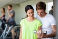 Handsome man personal trainer helping fit woman working with dumbbells in fitness gym club Royalty Free Stock Photo