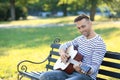 Handsome man playing guitar in park Royalty Free Stock Photo