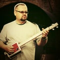 Handsome man playing his cigar box guitar Royalty Free Stock Photo