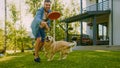 Handsome Man Plays Catch flying disc with Happy Golden Retriever Dog on the Backyard Lawn. Man Has Royalty Free Stock Photo