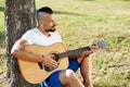 Handsome man plying guitar in a summer park Royalty Free Stock Photo