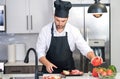 Handsome man is preparing food in kitchen. Handsome mature middle-aged man cooking meat in kitchen. Man preparing food Royalty Free Stock Photo