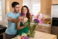 Handsome man and pretty woman are in love as newlyweds in their new home putting flowers into a vase Royalty Free Stock Photo