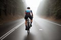 Handsome man in professional sports outfit trains on a bicycle outside the city in the woods on an asphalt road