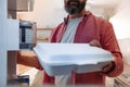 Handsome man putting takeaway container in fridge. Taking out lunch from fridge, eating leftovers. Stop trowing food Royalty Free Stock Photo