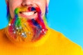 handsome man with raindow in beard with glitter confetti in blue studio baclground