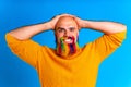 handsome man with raindow in beard and yellow sweater in blue studio baclground