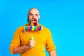 handsome man with raindow in beard and yellow sweater in blue studio baclground