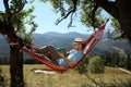 Handsome man reading book in hammock outdoors on sunny day Royalty Free Stock Photo