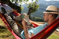 Handsome man reading book in hammock outdoors on sunny day Royalty Free Stock Photo