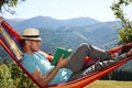 Handsome man reading book in hammock outdoors on sunny day Royalty Free Stock Photo