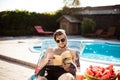 Handsome man reading book, lying on chaise near swimming pool. Royalty Free Stock Photo