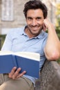 Handsome man reading book outdoors