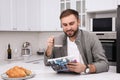 Handsome man reading magazine during breakfast at white marble table in kitchen Royalty Free Stock Photo