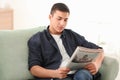 Handsome man reading newspaper on sofa at home Royalty Free Stock Photo