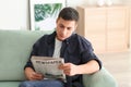 Handsome man reading newspaper on sofa at home Royalty Free Stock Photo