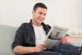 Handsome man reading newspaper on sofa at home Royalty Free Stock Photo